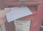 A ballot paper is posted into a red post box